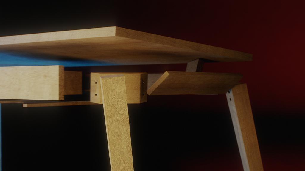 Ackon Desk joinery close-up: apron rail and leg fixed with two dowel pins under the pale timber top, black backdrop with red right and a hint of blue left