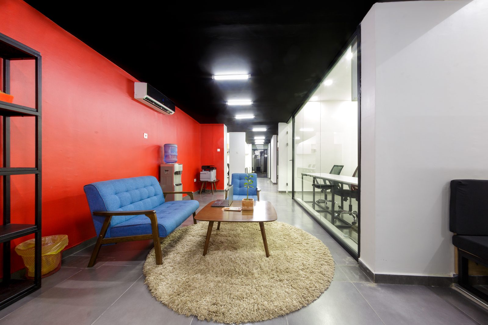 AFG - The same shelving and seating group from a wider angle, the glazed meeting rooms catching light along the right-hand wall.