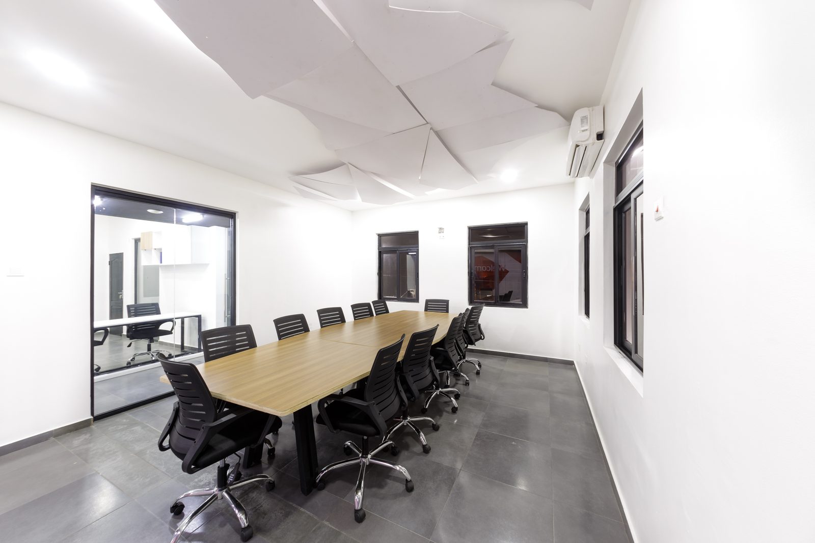 AFG - The opposite corner of the boardroom, windows on both walls and the geometric ceiling panels catching the daylight.