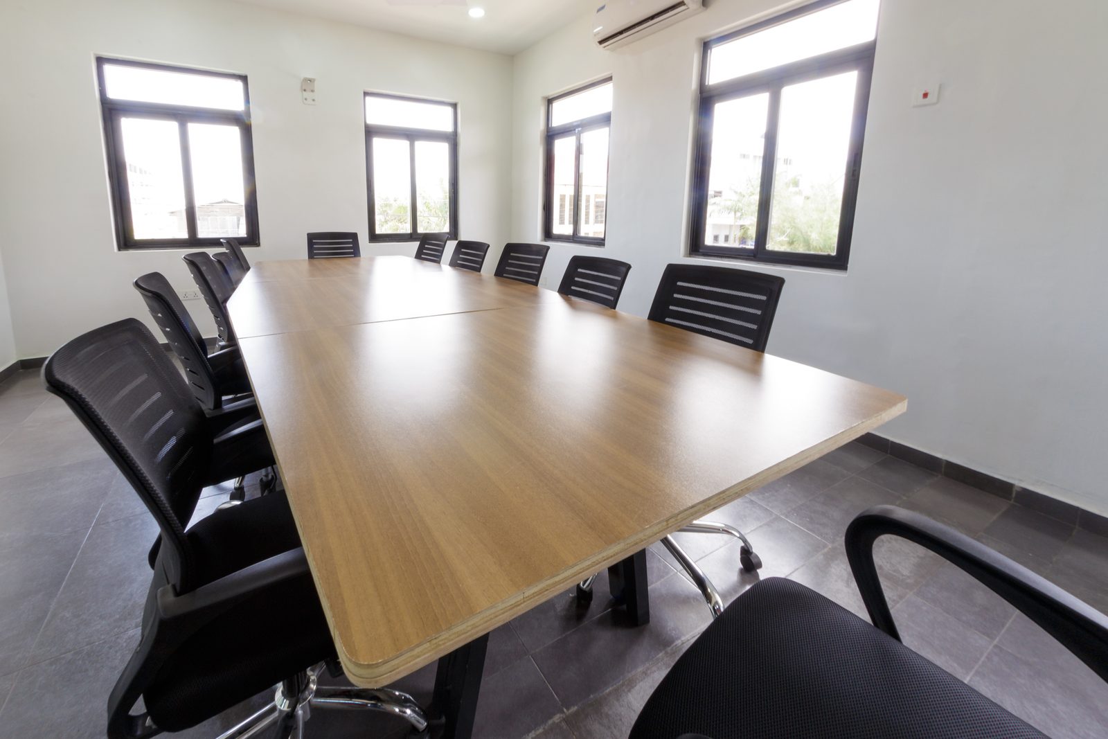 AFG - The corner of the plywood table and its black steel base, chairs in soft focus.
