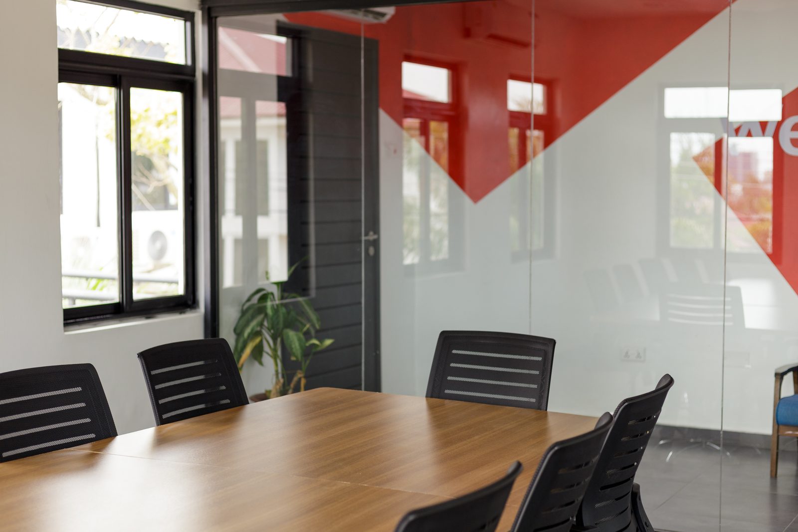AFG - The glazed corner of the boardroom with the red graphic wall and a plant beyond the door.