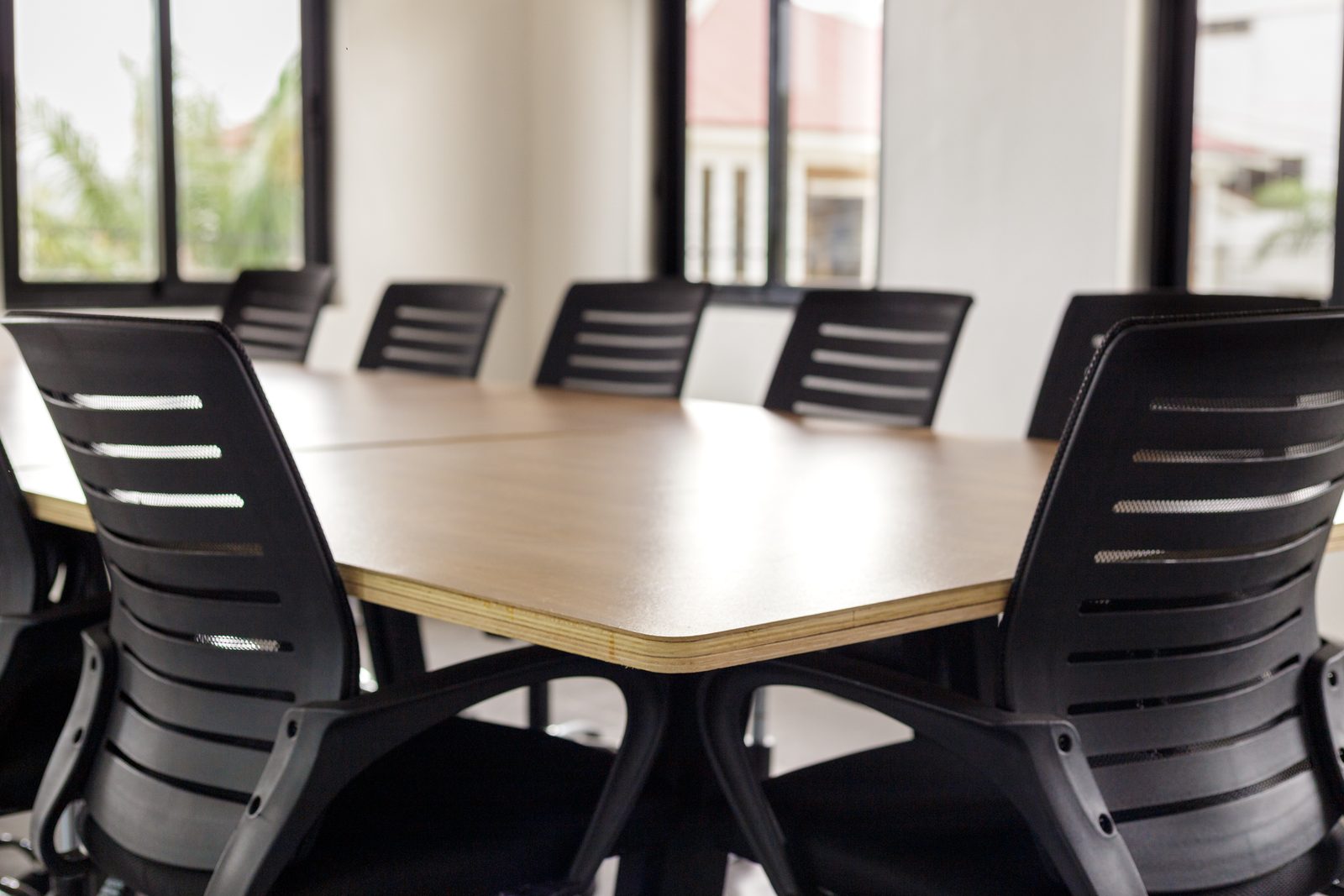 AFG - Chair backs and the plywood edge of the table, the room dimming towards the windows.