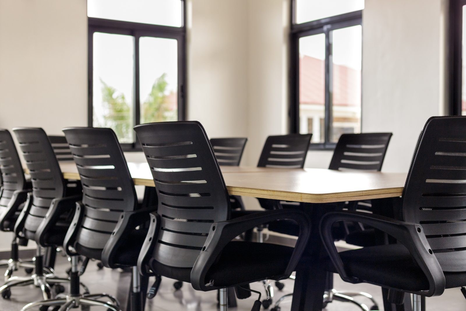 AFG - Detail of a black mesh conference chair at the table, its chrome base on the charcoal tiles.