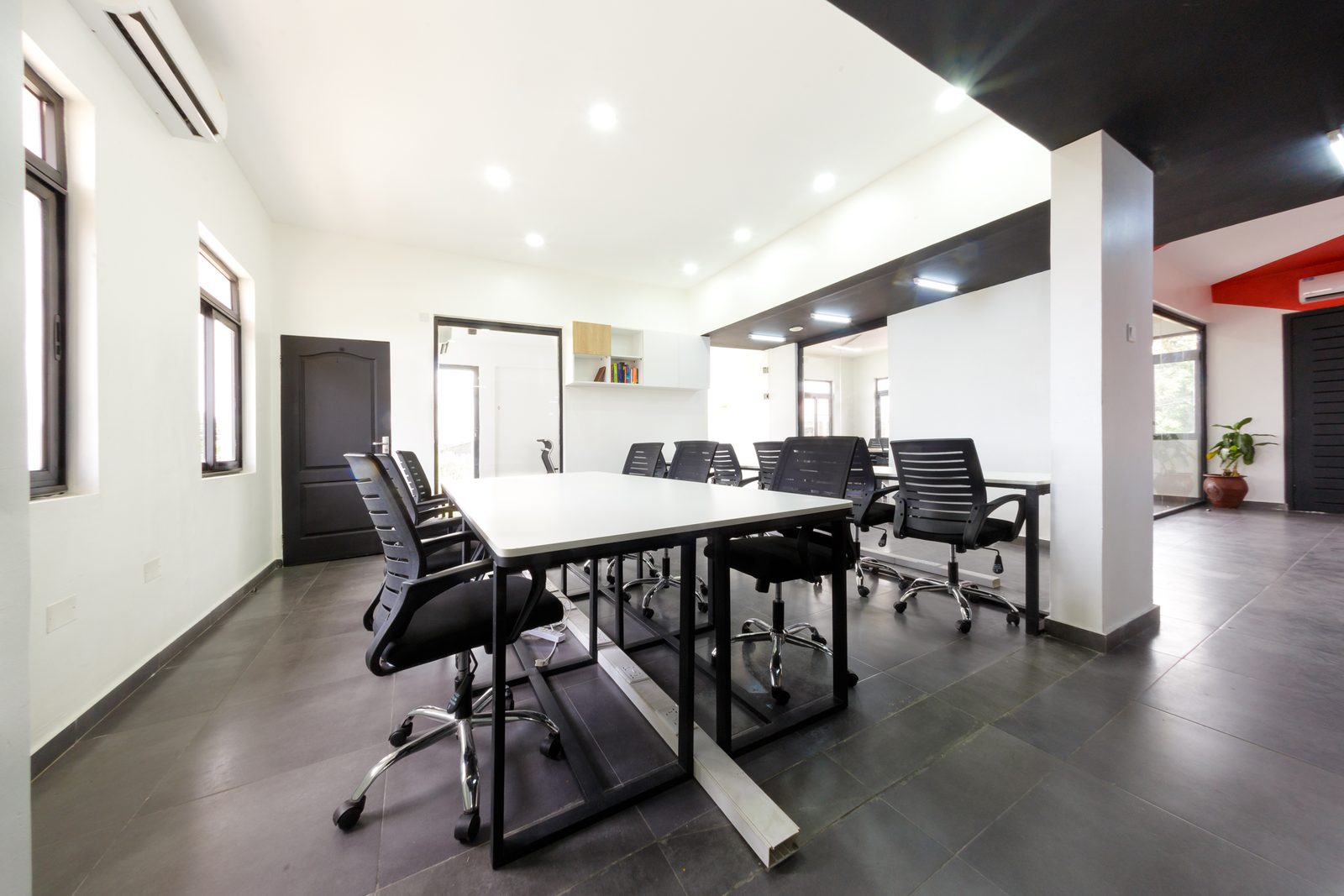 AFG - A second bank of workstations, the desks on black steel frames running towards a glazed door.