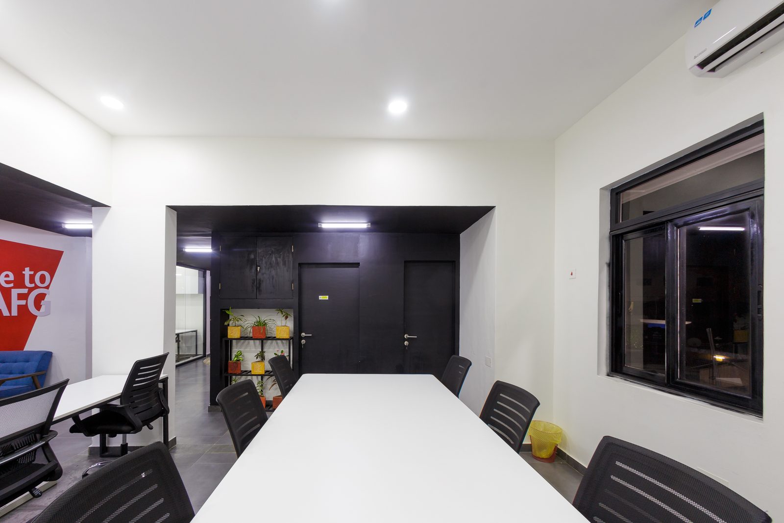 AFG - The far end of the workspace with a long meeting table and black doors, the office running back towards the lounge.