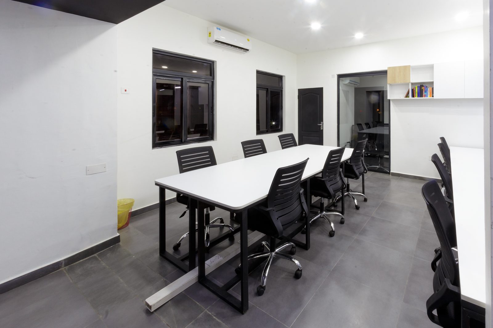 AFG - A short run of desks against a white wall with high windows and wall storage above.