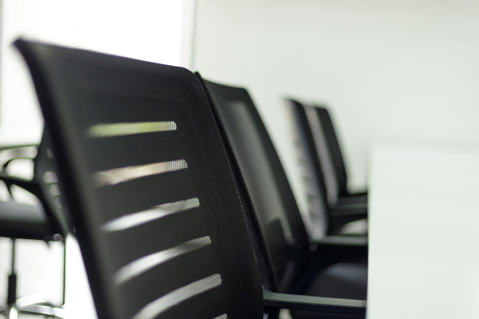 AFG - A row of black task chairs seen along the desk line, the nearest chair out of focus.