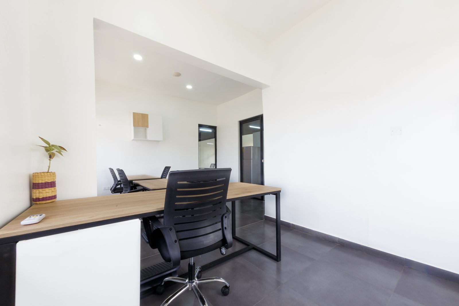 AFG - The partner's office from the door, a long desk against a white wall with wall storage and a glazed inner window.