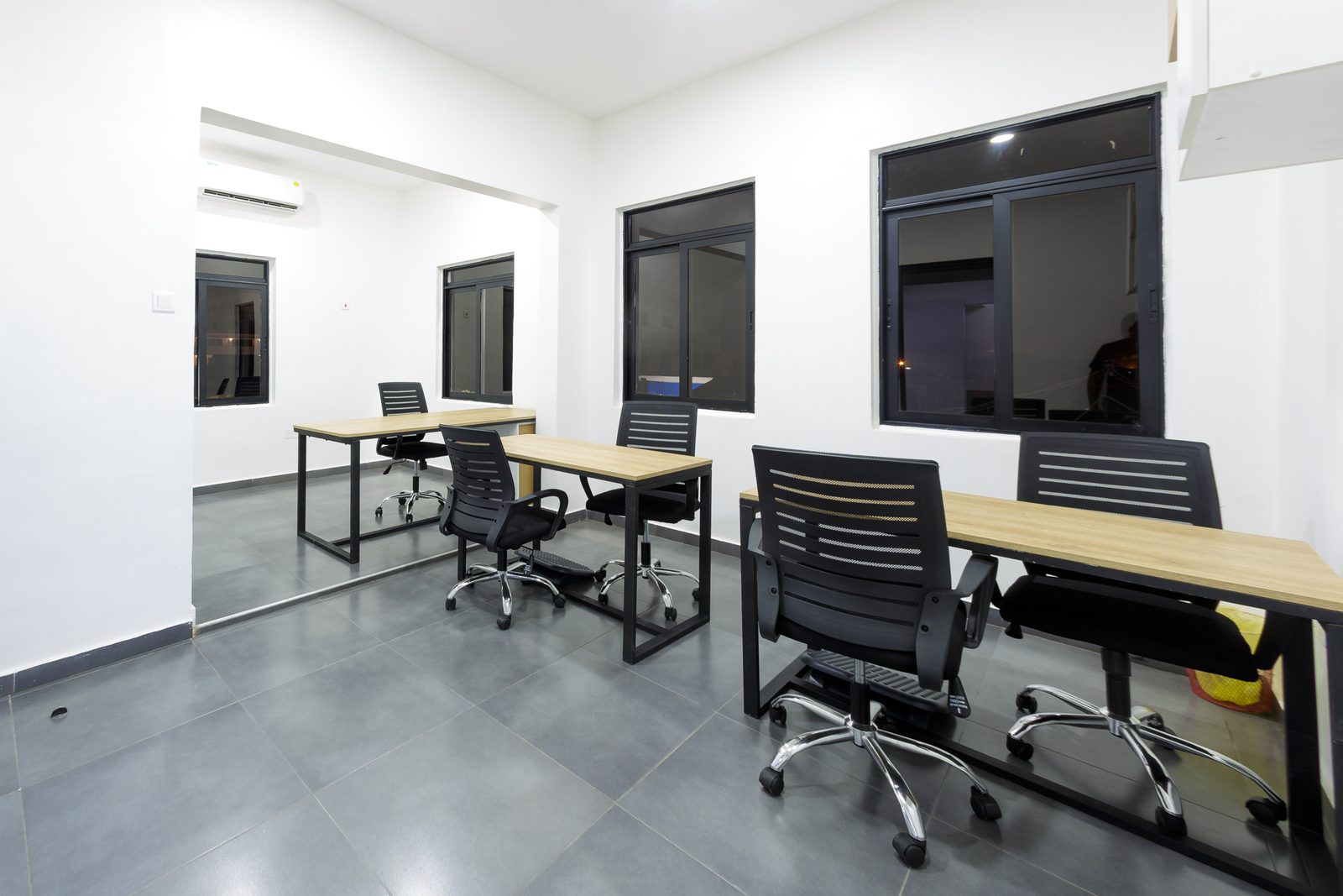AFG - A third angle of the management office, desks in two rows under high windows.