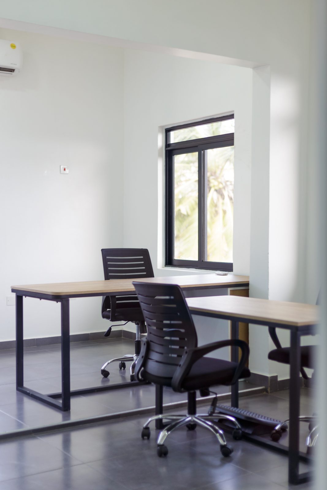 AFG - Portrait view of a single desk, its black frame and task chair against a white wall.