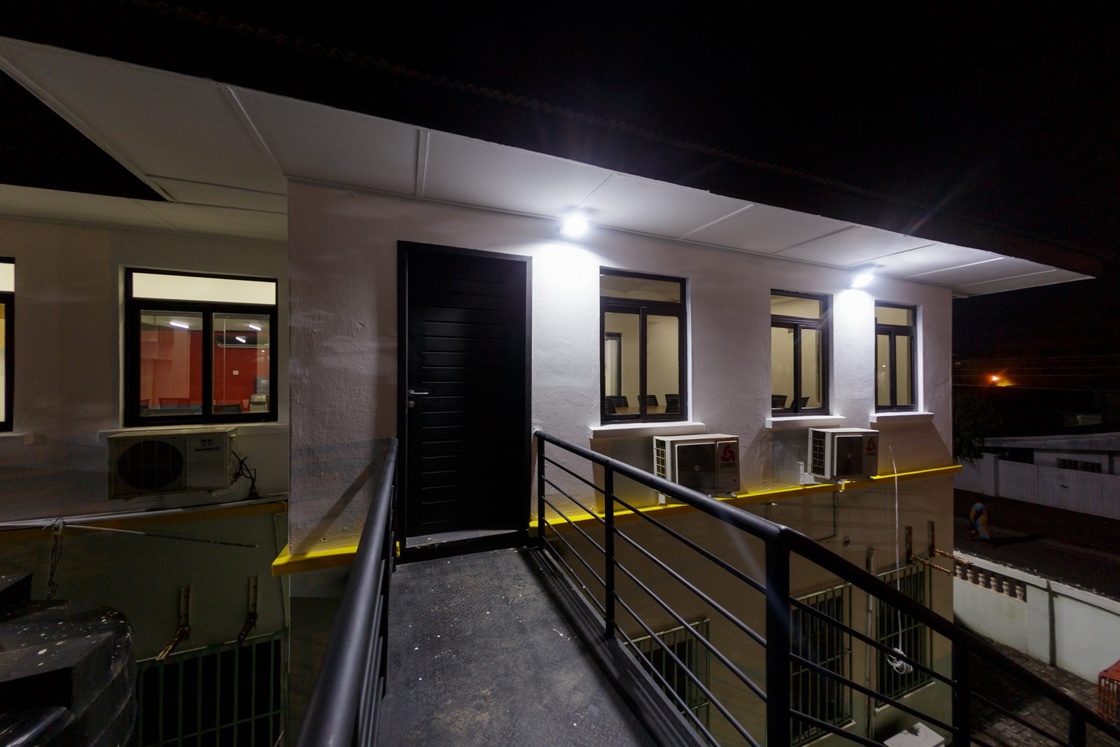 AFG - The building at night, wall-mounted floodlights picking out the entrance and the first-floor glazing.
