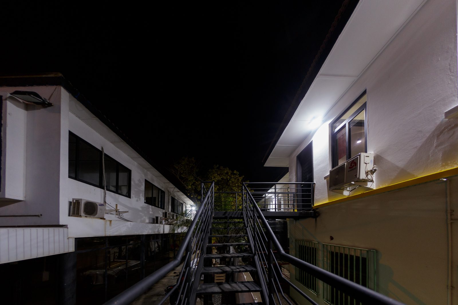 AFG - The external stair after dark, lit from above with the ground-floor windows glowing beyond.