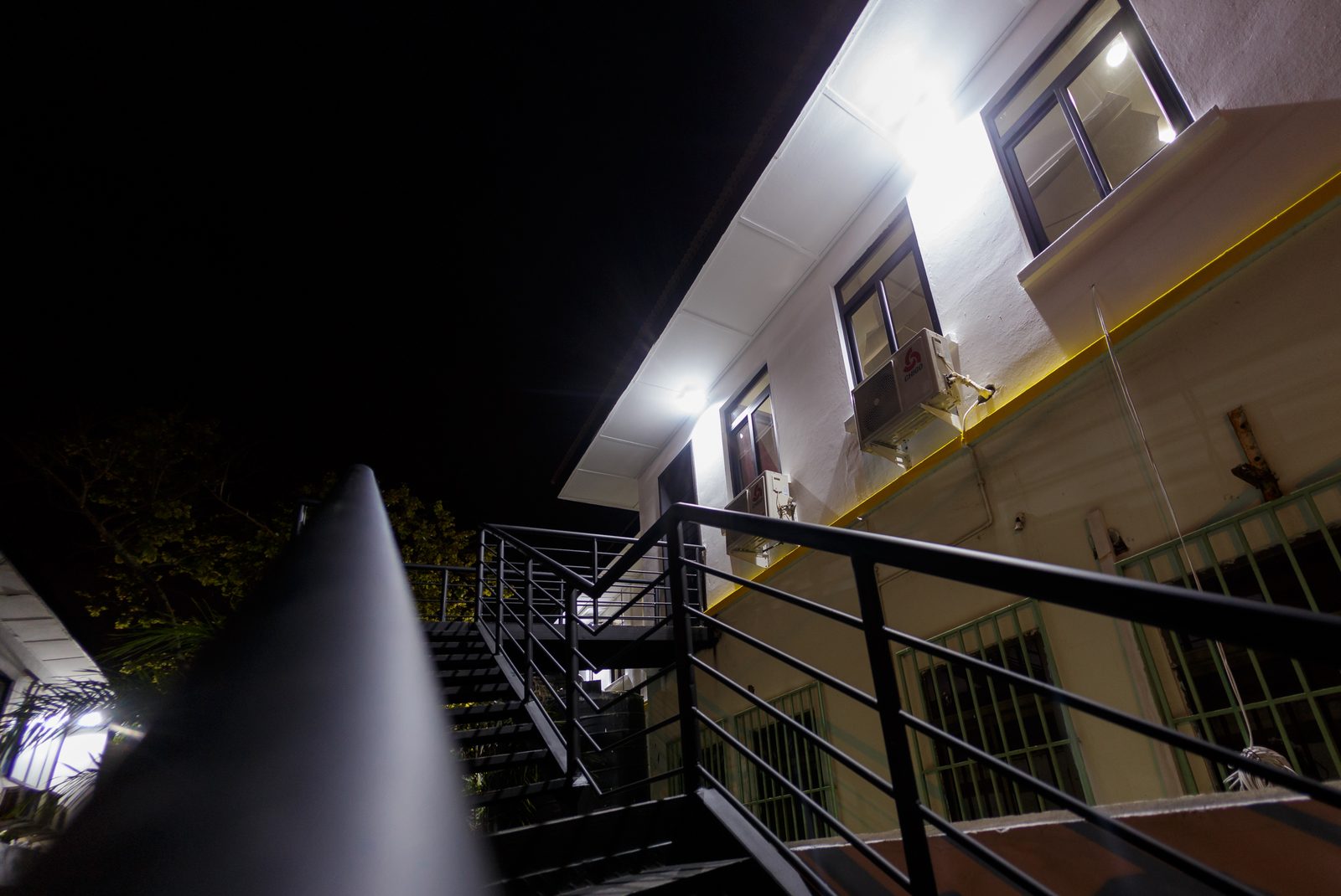 AFG - Looking up the black steel stair at night, its balustrade catching the floodlight.