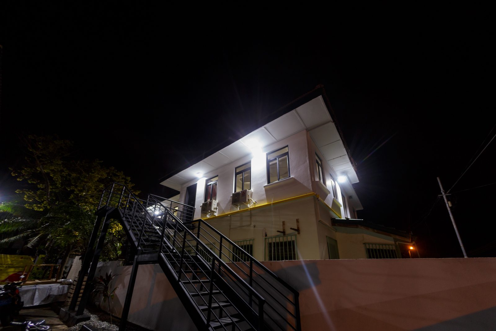 AFG - The whole building at night from across the yard, the stair silhouetted against the lit facade.