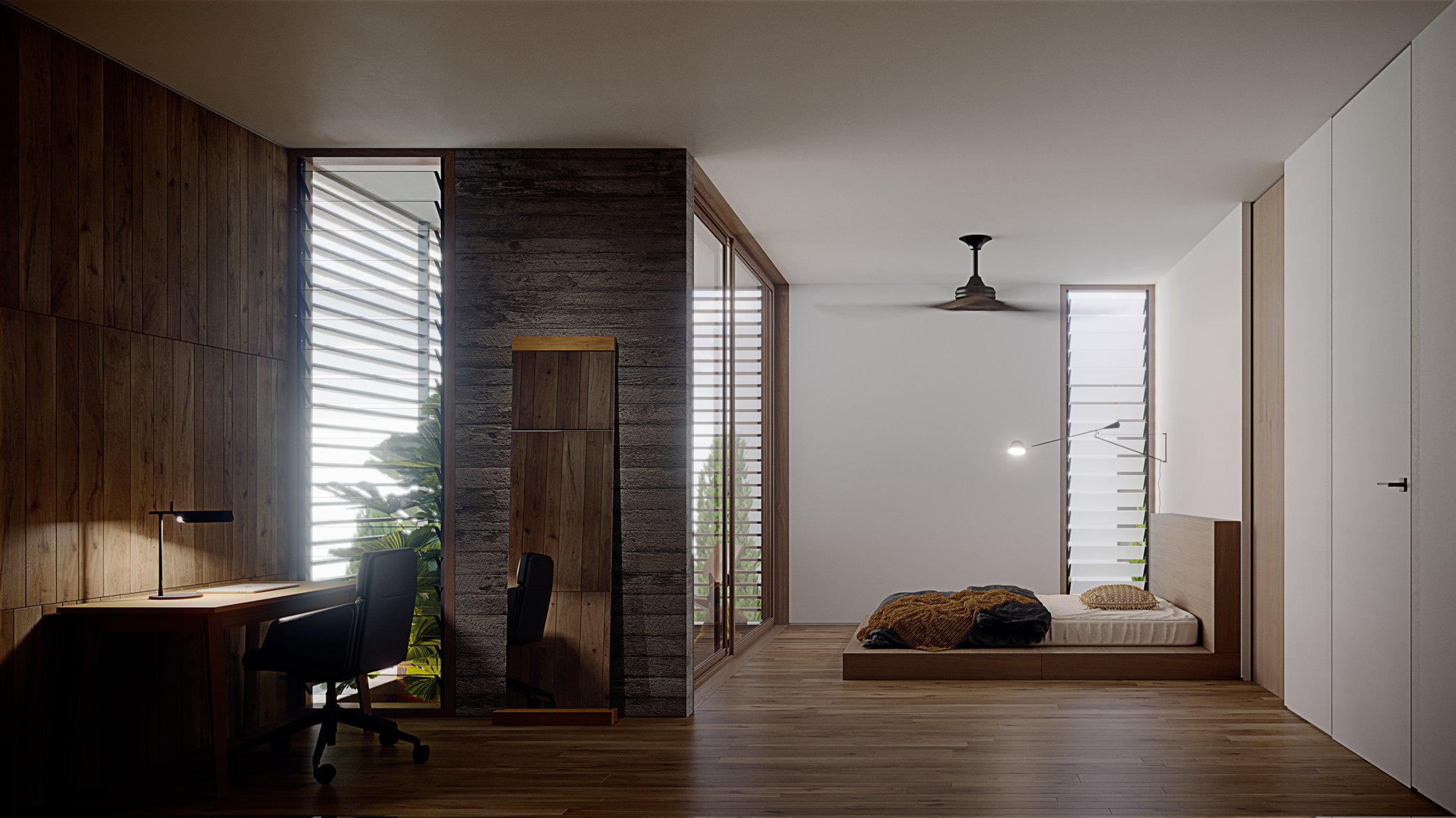 Ahero freestanding mirror in a daylight bedroom: the tall oak-capped mirror leans against a rough stone screen between an oak desk and a low platform bed, louvred windows throwing striped shadows across the timber floor.
