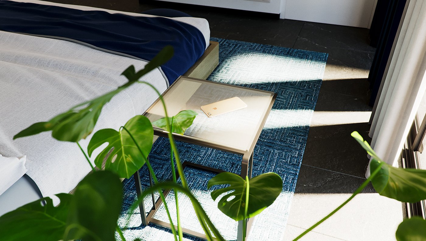 Detail render from the bedside: monstera leaves in the foreground, a glass side table with an open book, the white duvet and navy throw, and strong bands of sunlight falling across the teal patterned rug.