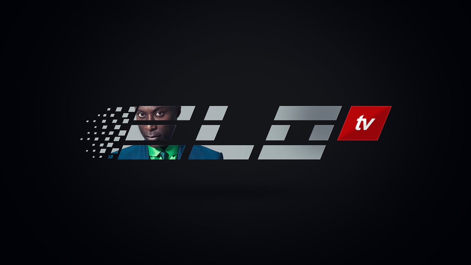 ELO TV ident frame: a man in a blue blazer, green shirt and patterned tie looking into camera through the silver-grey letterforms, the pixel trail at left and a red tv block at right.