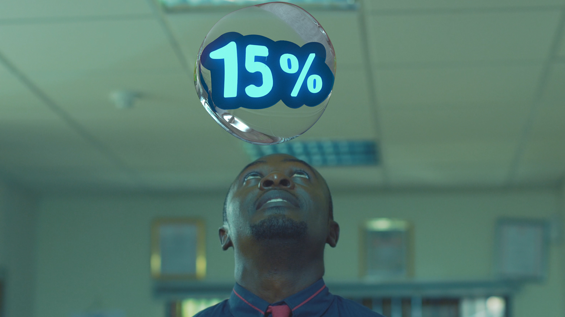 HFC TVC the same office frame as the header: man in a navy shirt with a red-trim collar looking up at the glass bubble and its blue 15% text.