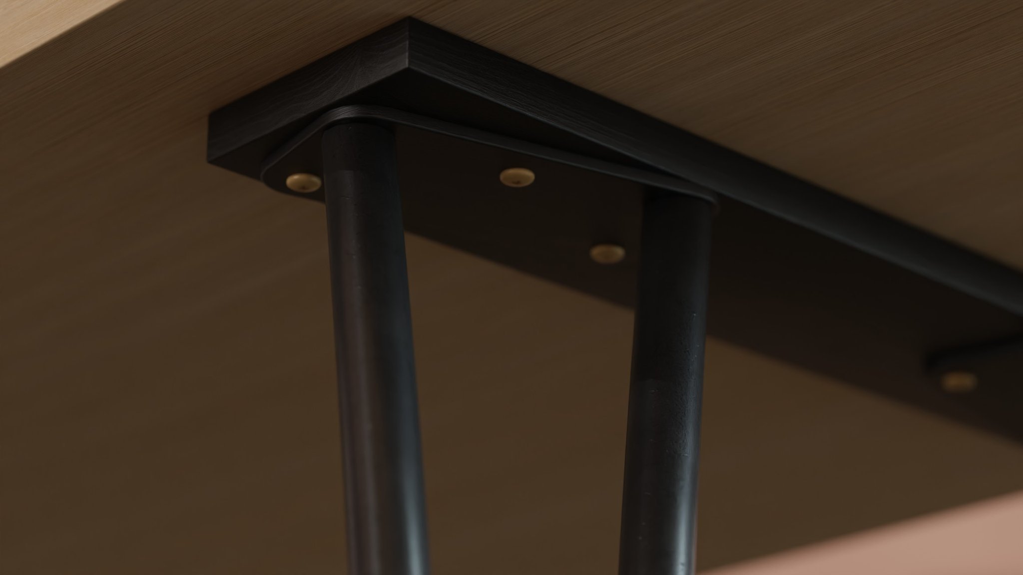 Lamu leg fixings from underneath: black tubular legs hung from a mitred black steel bracket, its brass screw caps showing against the pale oak underside.