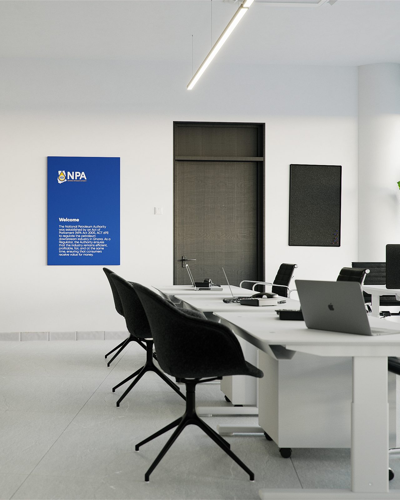 Portrait crop of the brand wall: the blue NPA panel carrying the Authority's welcome statement, behind a bank of white desks with black shell chairs and two open laptops.