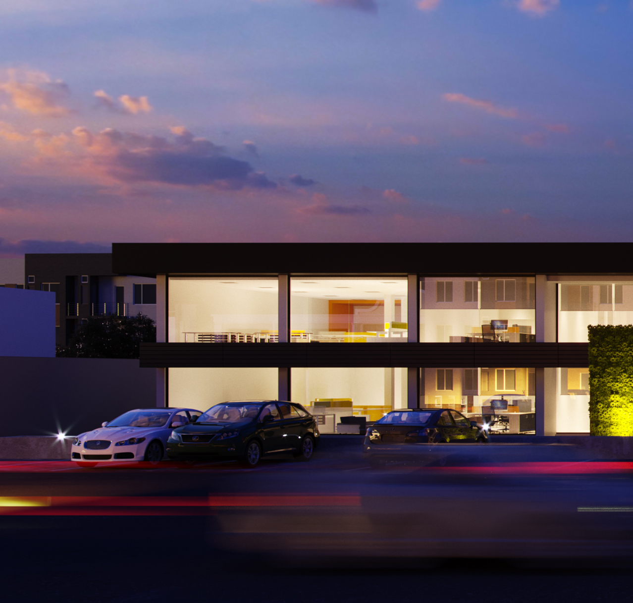 Palazzo offices at dusk: two glazed storeys banded in dark fascia, desks, partitions and yellow accents lit inside, a white saloon and two dark cars parked in front and an uplit hedge at the right under pink cloud