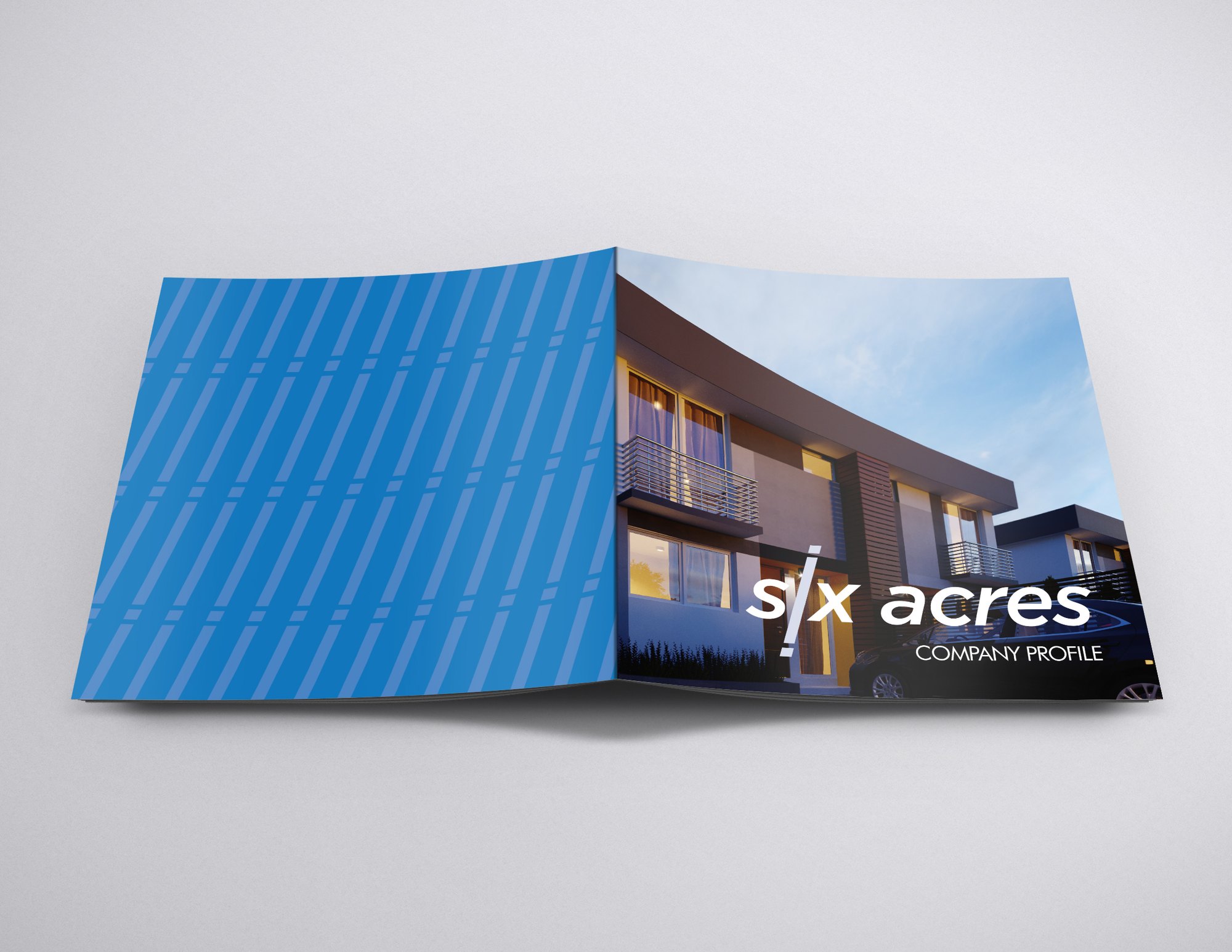 The profile stood and folded open: the pale blue striped back cover behind the front, its dusk house render and white six acres wordmark facing the viewer