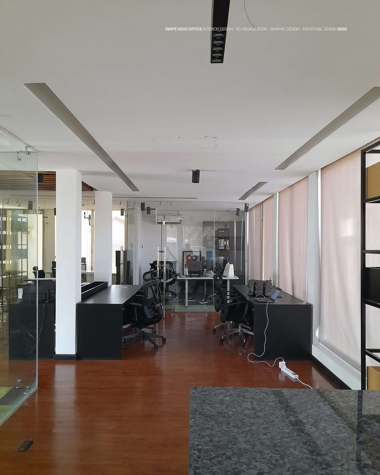 Swipe - the fitted-out head office photographed after handover: black desks and mesh task chairs on a polished timber floor, glazed meeting rooms and white columns on the left, full-height blinds down the window wall, and the studio's caption line across the top