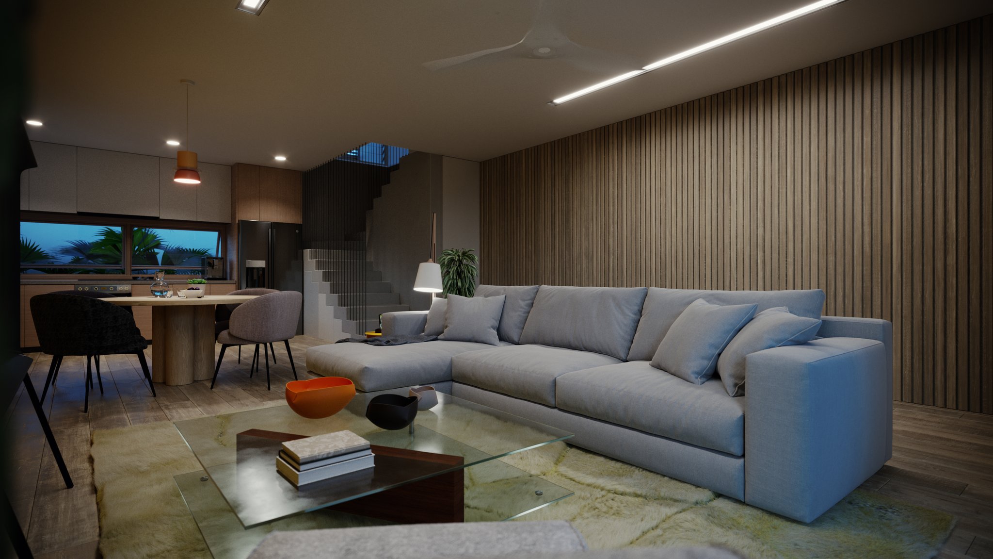 TTD living room: grey L-shaped sectional, timber slat wall and a glass coffee table with orange and black bowls, sheepskin rug, palms at dusk.