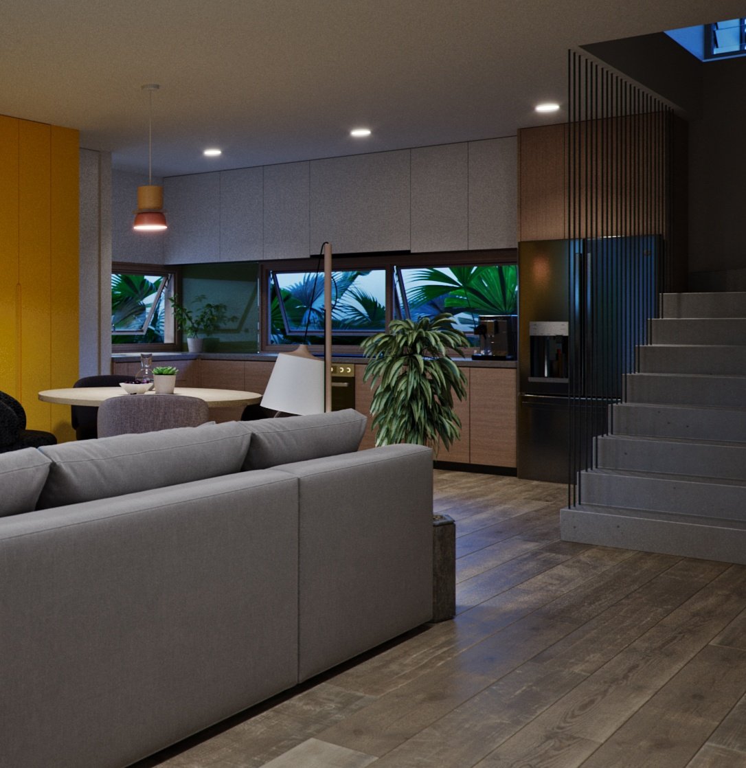 TTD open-plan living at dusk: grey sofa back in the foreground, wood pendant over the round dining table, kitchen with grey and wood cabinets and a concrete stair.